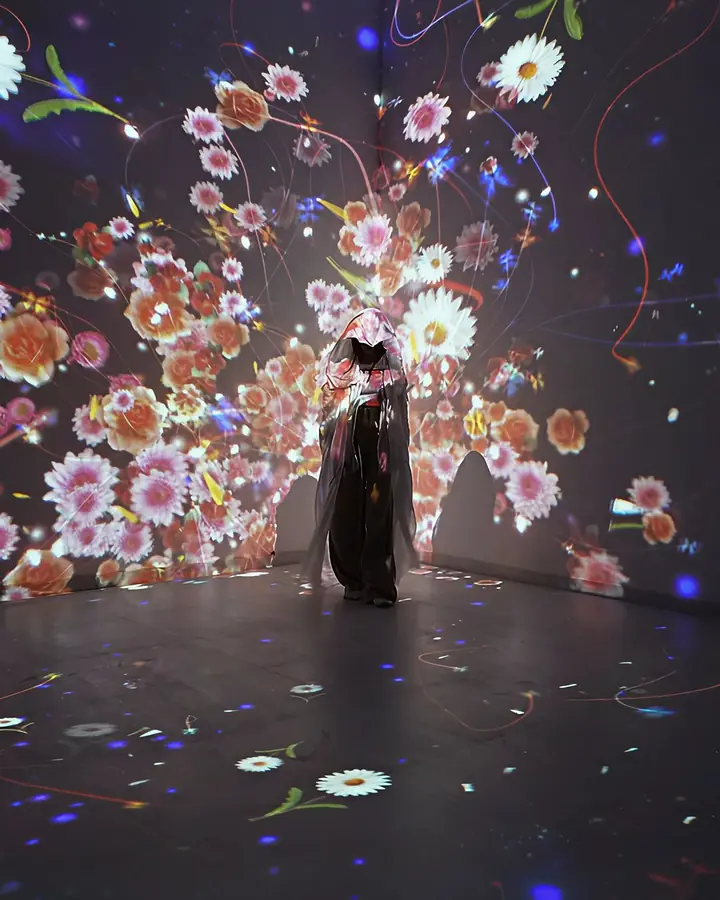 A visitor stands in a room of projected white and yellow flowers.