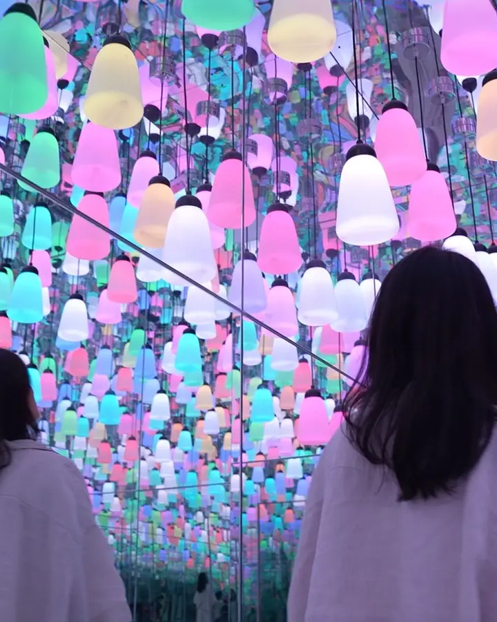 A visitor looks up at hundreds of coloured lamps.